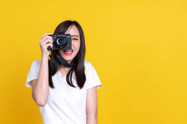 азиатская женщина улыбается красивая девушка в белой рубашке, принимая фото на камеру изолированы на цветном фоне - photographer enjoyment elegance old fashioned стоковые фото и изображения