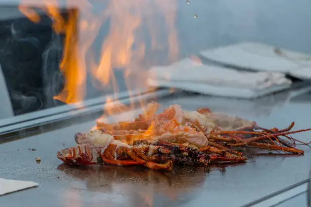 Cooking a spine lobsert on a teppanyaki grill with flames erupting