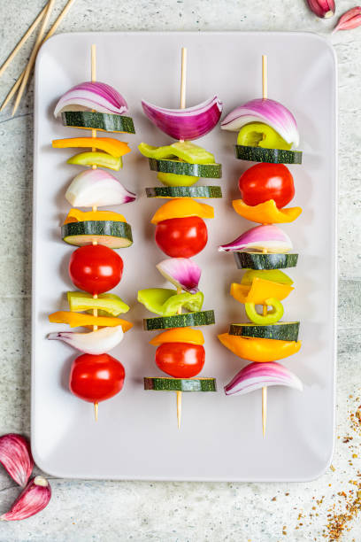 istock Cooking raw vegetable skewers on gray rectangular plate, top view. Vegan food concept. 1249796561