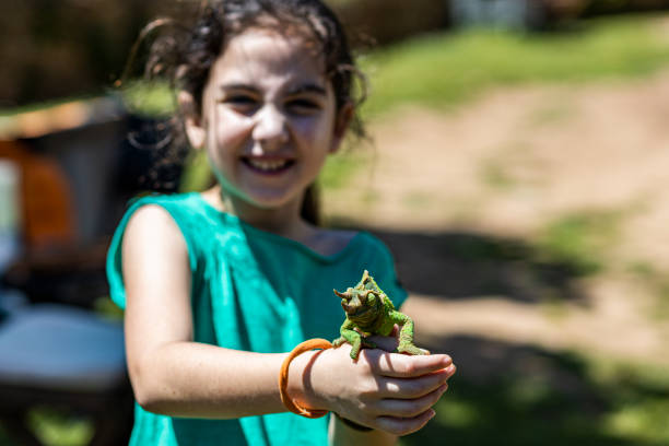 istock Little girl with a chameleon on her hands 1249798799