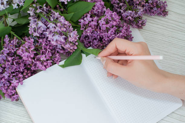 istock Lilac on a wooden table. An open notebook and a pen. 1249798902