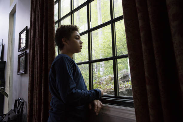 Mixed race kid looking through the window in lockdown