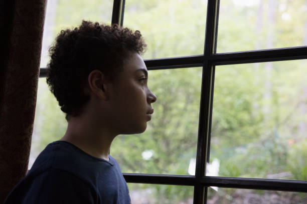 istock Mixed race kid looking through the window in lockdown 1249799110