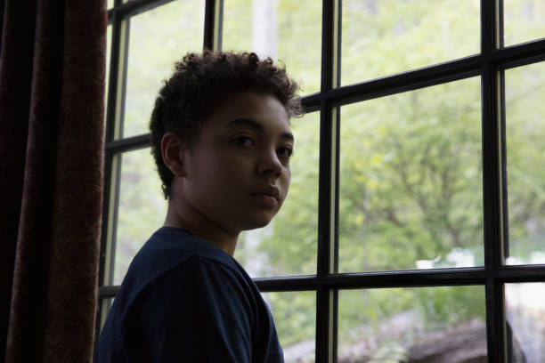 istock Mixed race kid looking through the window in lockdown 1249799131