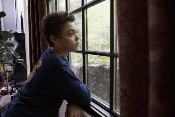istock Mixed race kid looking through the window in lockdown 1249799591