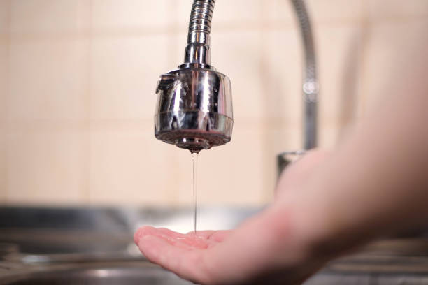 istock a man opens a faucet in the kitchen, but no water comes. Overlapping water 1249801394