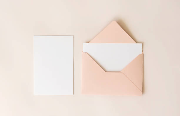 istock Mockup blank letter inside pink envelope and white paper on beige background, top view. Greeting card concept. Wedding invitation template 1249802374