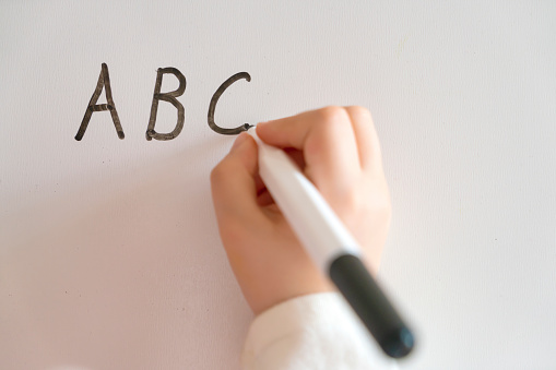 Child writing Alphabet on Dry Erase Whiteboard