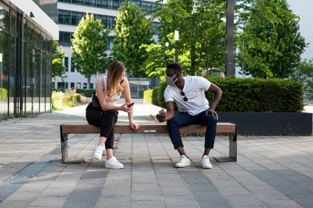 istock Young Man and Woman Social Distancing on Bench Using Phones 1249806425