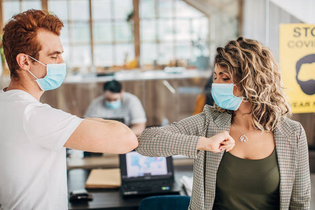 istock Two colleagues greeting each other with elbows in office during coronavirus pandemic 1249808944