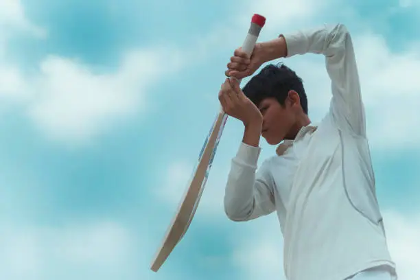 Photo of A boy in cricket uniform and doing batting practice.