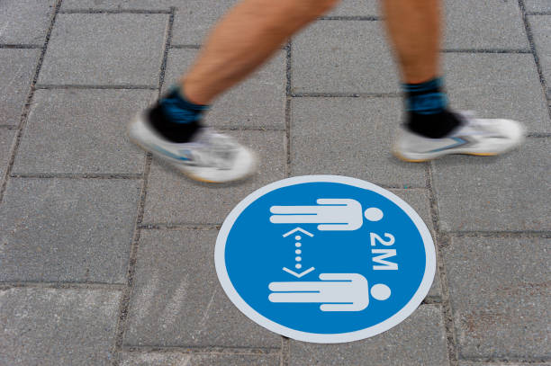 Sign printed on ground informing people to keep a 2 meter distance from each other during Covid-19 pandemic.
