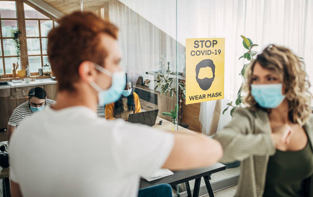 istock Coworkers greeting each other with elbows in office during coronavirus time 1249812947