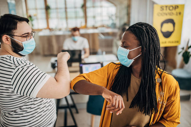 istock Colleagues greeting each other with elbows in office during coronavirus pandemic 1249813236