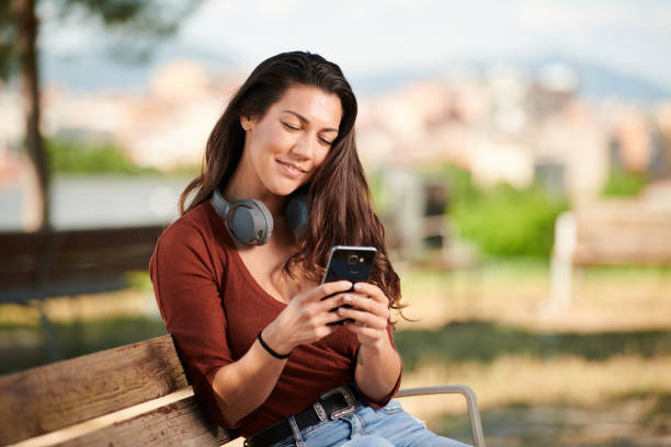 istock young girl sat on a bench with a mobile phone 1249813360