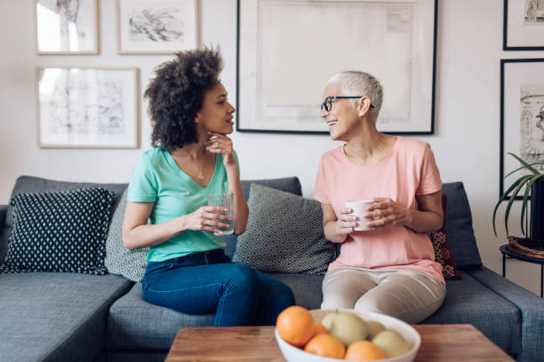 femme aîné et son jeune voisin appréciant parler - friendship coffee home interior women photos et images de collection