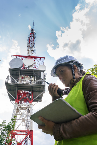 Engineer working on the field near a city Telecomunications tower, checking the condition of the Equipement. Technology and Global Business.