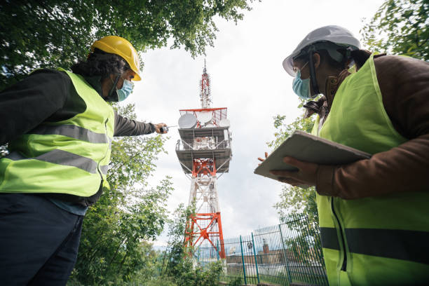istock Two colleagues engineers wearing protective face masks during the COVID-19 pandemic. Working on the field near a Telecommunications tower. Teamwork while coronavirus outbreak. 1249817809