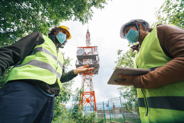 istock Two colleagues engineers wearing protective face masks during the COVID-19 pandemic. Working on the field near a Telecommunications tower. Teamwork while coronavirus outbreak. 1249817815