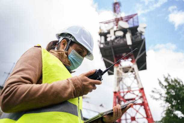 istock Female Engineer wearing a protective face mask during the COVID-19 pandemic. Working on the field near a Telecommunications tower while coronavirus outbreak. 1249817820