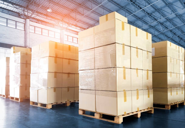 istock Stack of shipments boxes on wooden pallets at interior of warehouse storage. 1249823845