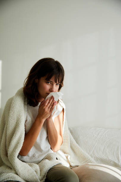 istock Sick young woman sitting on her bed with a cold 1249828495