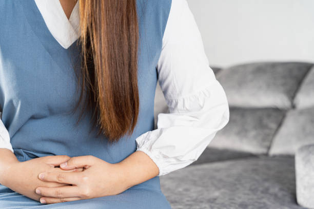 istock Young woman suffering from strong abdominal pain or menstruation while sitting on sofa at home. Healthcare medical or daily life concept. 1249835013