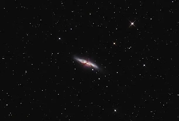 M82, as this irregular galaxy is also known, was stirred up by a recent pass near large spiral galaxy M81. This doesn't fully explain the source of the red-glowing outwardly expanding gas, however. Recent evidence indicates that this gas is being driven out by the combined emerging particle winds of many stars, together creating a galactic "superwind". The filaments extend for over 10,000 light years. The 12-million light-year distant Cigar Galaxy is the brightest galaxy in the sky in infrared light, and can be seen in visible light with a small telescope towards the constellation of Ursa Major.