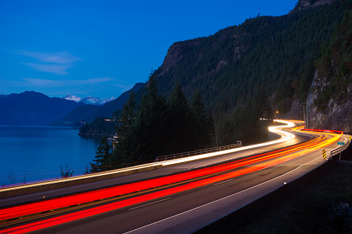 The stunning Sea to Sky Highway north of Vancouver. Traffic lights motion blurred along a scenic coastal highway. Transportation and travel concepts.