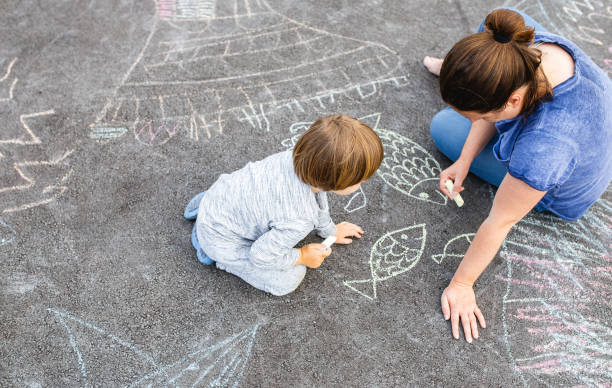 istock Young boy doodling on asphalt with his mother 1249838668