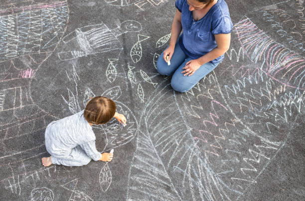istock Young boy doodling on asphalt with his mother 1249838671