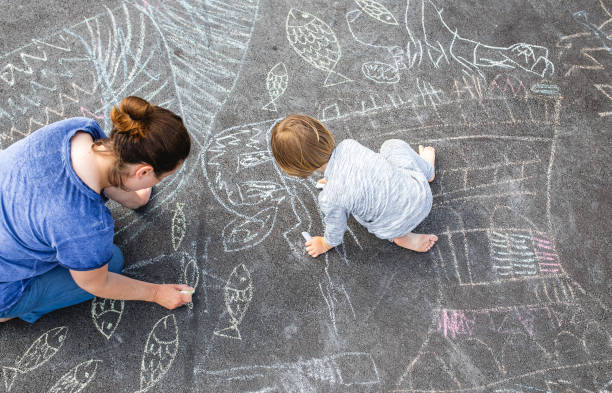 istock Young boy doodling on asphalt with his mother 1249838679