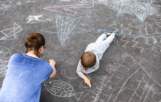 istock Young boy doodling on asphalt with his mother 1249838748