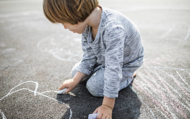 istock Young boy doodling the asphalt with a chalk 1249838825