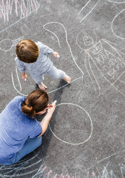 istock Young boy doodling on asphalt with his mother 1249838885