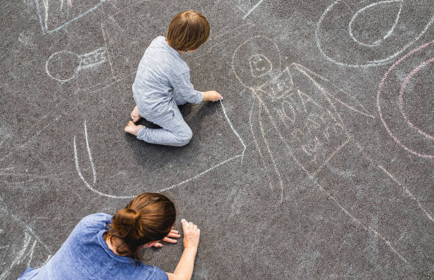istock Young boy doodling on asphalt with his mother 1249838886