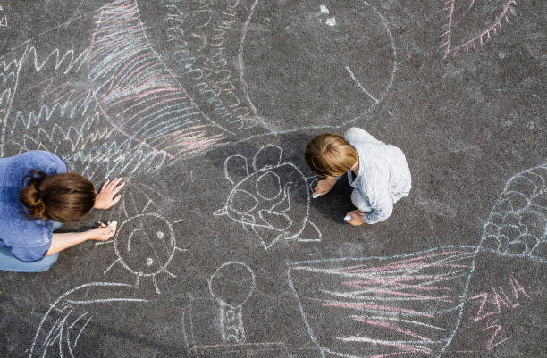 istock Young boy doodling on asphalt with his mother 1249839149