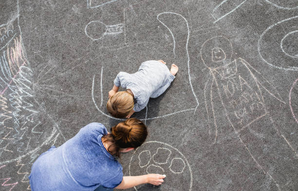 istock Young boy doodling on asphalt with his mother 1249839753