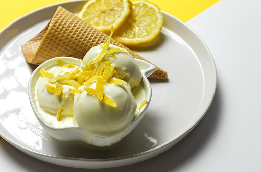 Homemade and refreshing natural lemon ice cream ball in cone on colors background