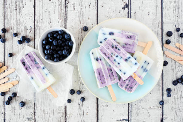 istock Blueberry yogurt ice pops, top down table scene over white wood 1249842537