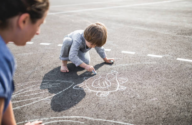 istock Young boy doodling on asphalt with his mother 1249842699