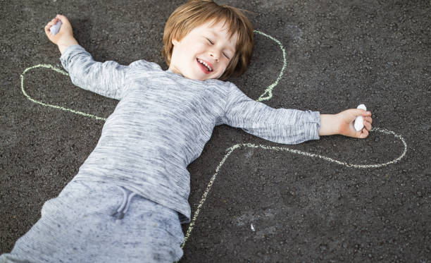 Boy lying down in his own outline drawn with a chalk