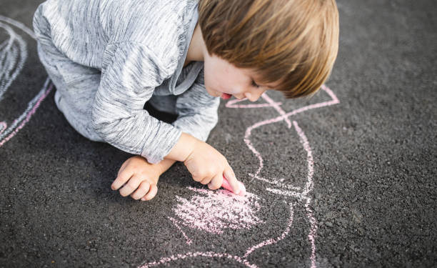 istock Young boy doodling the asphalt with a chalk 1249842938