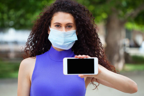 istock Young woman with a protective face mask using smart phone 1249843442