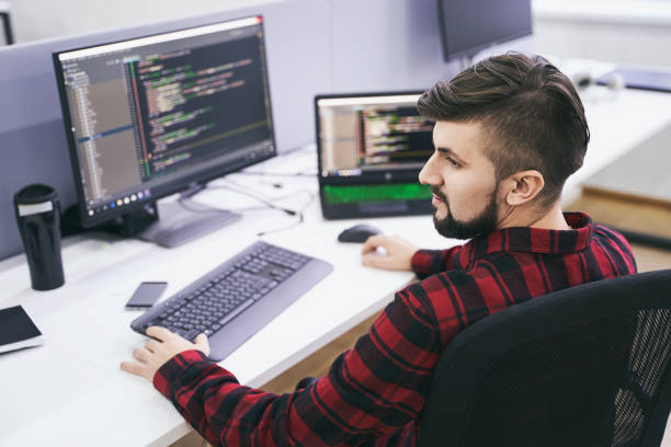 Software developer working on computer in IT office, sitting at desk and coding, working on a project in software development company or technology startup. High quality image. stock photo
