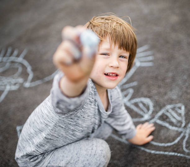 istock Young boy doodling the asphalt with a chalk 1249843488