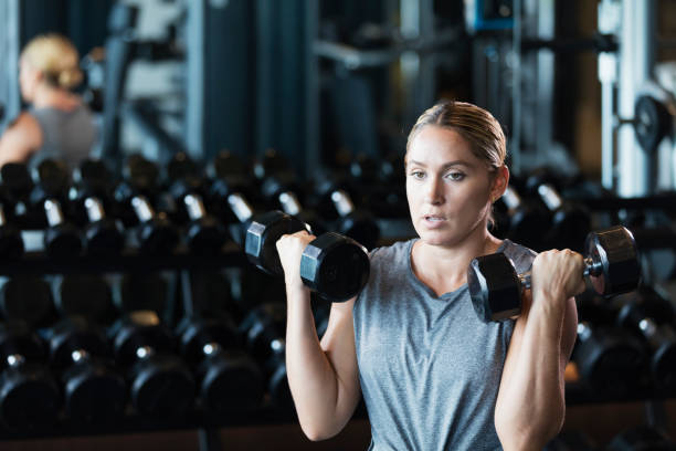 istock Hispanic woman working out at gym, lifting dumbbells 1249844148