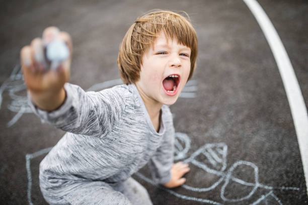 istock Young boy doodling the asphalt with a chalk 1249844252