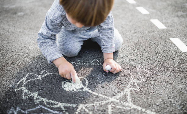 istock Young boy doodling the asphalt with a chalk 1249844285
