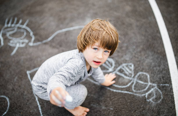 istock Young boy doodling the asphalt with a chalk 1249844319